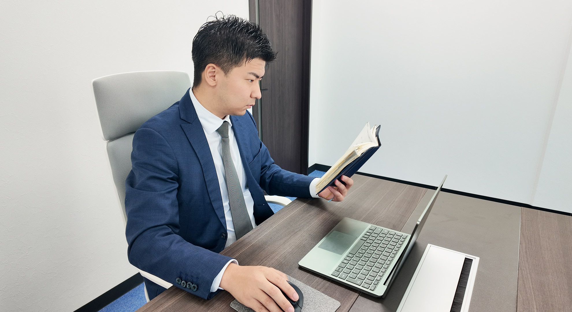 朝のデスクで、手帳とPCを使って1日の計画を立てる藤川さん